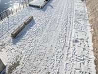 a person standing in the snow on the edge of a walkway at a lake bank