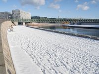 this is a snowy area where there is snow on the ground and benches are near the water