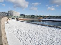 this is a snowy area where there is snow on the ground and benches are near the water