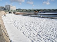 this is a snowy area where there is snow on the ground and benches are near the water