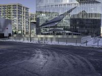 two large buildings in the snow on an empty road and some glassy buildings with glass in the background