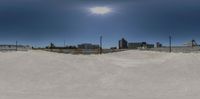 a large skateboard park with snow around it and a sun behind the ramp and fence