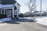 the white house has snow piled on its sidewalk and front door, two front porchs with columns