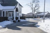 the white house has snow piled on its sidewalk and front door, two front porchs with columns