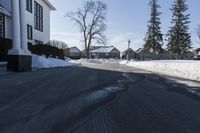 the white house has snow piled on its sidewalk and front door, two front porchs with columns