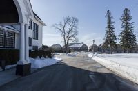 the white house has snow piled on its sidewalk and front door, two front porchs with columns