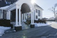 the white house has snow piled on its sidewalk and front door, two front porchs with columns