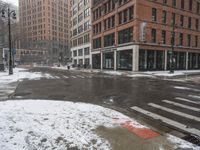 an empty city street during a snow storm with cars parked on the curb and building behind it