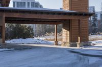 an empty garage and car port covered in snow in front of a high rise building