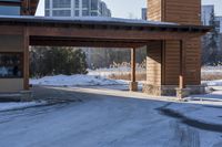 an empty garage and car port covered in snow in front of a high rise building