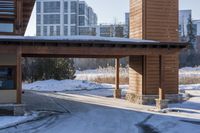 an empty garage and car port covered in snow in front of a high rise building