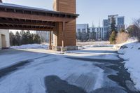 an empty garage and car port covered in snow in front of a high rise building