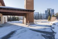 an empty garage and car port covered in snow in front of a high rise building