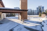 an empty garage and car port covered in snow in front of a high rise building