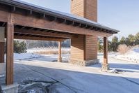 an empty garage and car port covered in snow in front of a high rise building