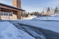 an empty garage and car port covered in snow in front of a high rise building