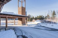 an empty garage and car port covered in snow in front of a high rise building