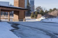 an empty garage and car port covered in snow in front of a high rise building