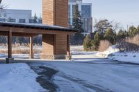 an empty garage and car port covered in snow in front of a high rise building