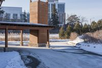 an empty garage and car port covered in snow in front of a high rise building