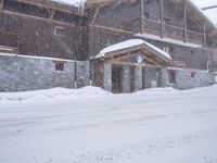 a tall brown wooden house with several windows in the snow near a road with a person walking up the sidewalk next to it