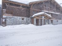 a tall brown wooden house with several windows in the snow near a road with a person walking up the sidewalk next to it