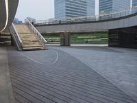 an empty walkway and steps leading to many skyscrapers in the city park area of a city