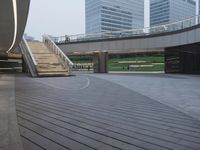 an empty walkway and steps leading to many skyscrapers in the city park area of a city