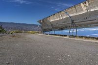 a solar panel on the side of a road in the desert with mountains in the background