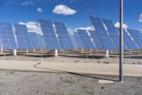 rows of solar panels on the ground with a pole and blue sky in the background