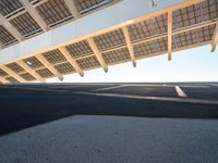 a long empty parking lot with some roof top solar panels over it, near the ocean