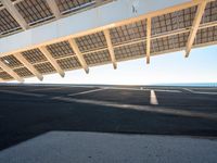 a long empty parking lot with some roof top solar panels over it, near the ocean