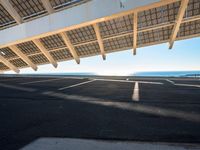 a long empty parking lot with some roof top solar panels over it, near the ocean