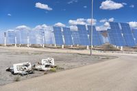 several pieces of an object are in the dirt near a row of solar panels in the desert