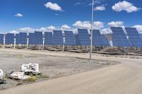 several pieces of an object are in the dirt near a row of solar panels in the desert