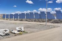 several pieces of an object are in the dirt near a row of solar panels in the desert