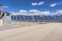 a large field of solar panels in front of a building with barbed fencing on the side of it