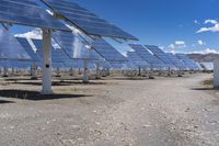 large solar panels are sitting in the desert beneath a blue sky and clouds is shown here