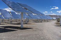 large solar panels are sitting in the desert beneath a blue sky and clouds is shown here