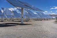 large solar panels are sitting in the desert beneath a blue sky and clouds is shown here