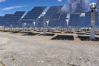 an array of solar panels sitting in the middle of nowhere below a cloudy blue sky