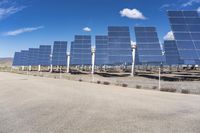 several rows of solar panels along the edge of an empty road in a rural area