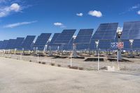 several rows of solar panels along the edge of an empty road in a rural area