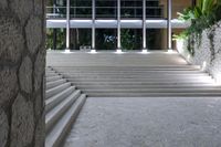 a stone staircase with some concrete steps and plants in front of a large glass building