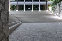 a stone staircase with some concrete steps and plants in front of a large glass building