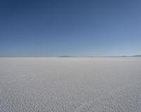 a lone person in the middle of a vast desert surface, looking to the left