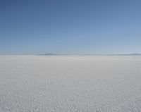 a lone person in the middle of a vast desert surface, looking to the left