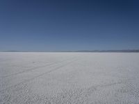 a lone person in the middle of a vast desert surface, looking to the left