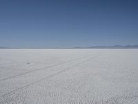 a lone person in the middle of a vast desert surface, looking to the left