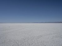 a lone person in the middle of a vast desert surface, looking to the left